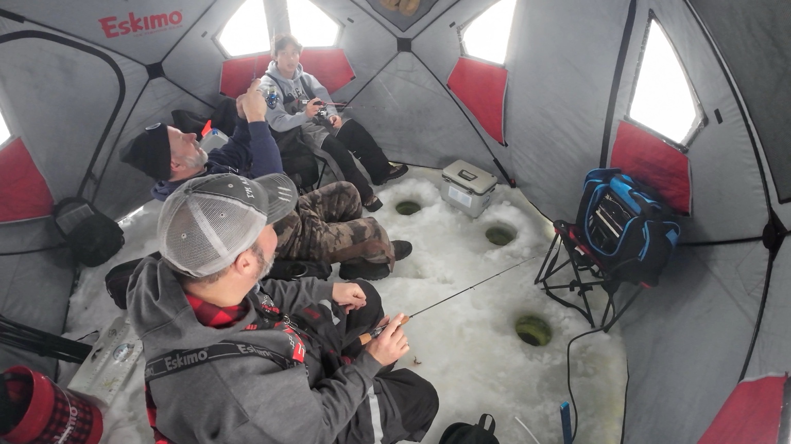 Fishing inside an Eskimo ice shelter with multiple holes in the ice